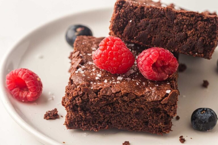 Fudgy sheet pan brownies topped with fresh raspberries and flaky salt.