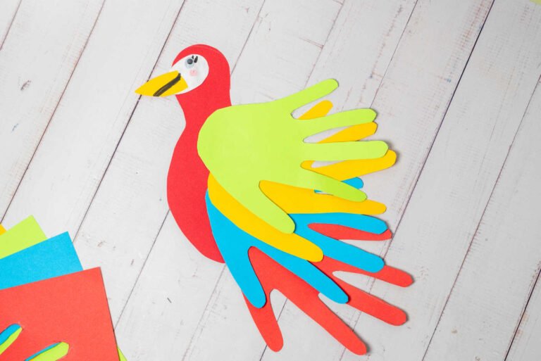 Colorful parrot handprint craft with layered paper feathers and detailed face.