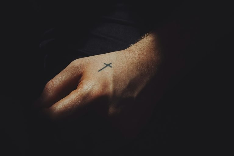 Christians and Tattoos featuring a small cross tattoo on a hand.