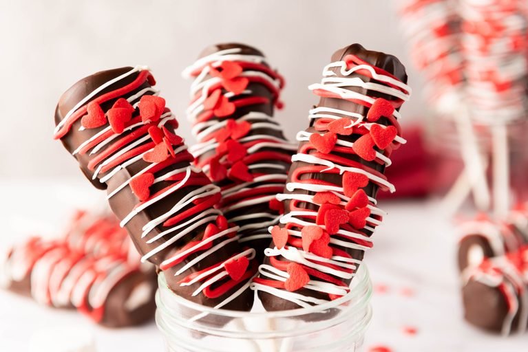 Valentine’s Day marshmallow pops with chocolate, heart sprinkles, and red and white drizzle.