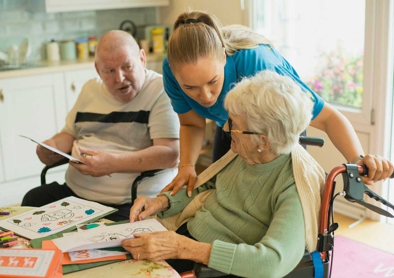 Caregiver assisting elderly residents in a care setting for an article about elder abuse in nursing home facilities.