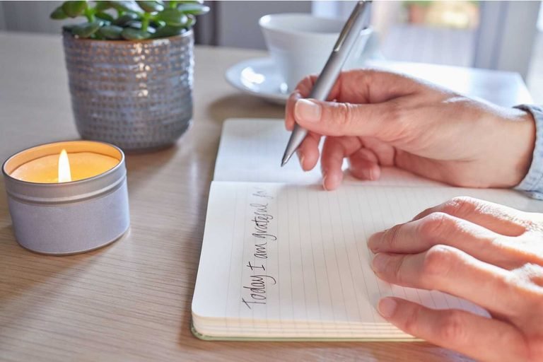 Faith journaling with a notebook, candle, and pen for Christian reflection and gratitude.
